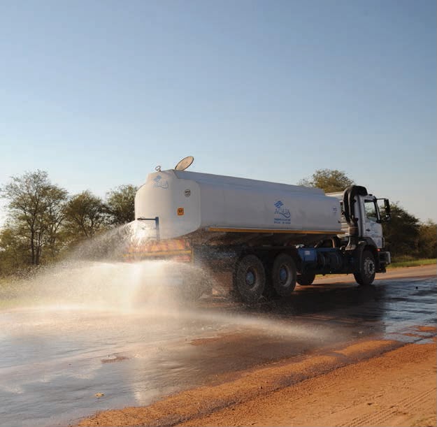 Water bowser truck spraying a gravel road